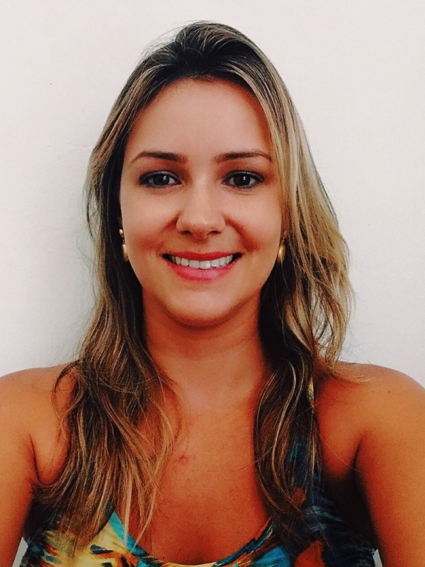 Mulher sorridente de pele clara, cabelos louros, ondulados e compridos.