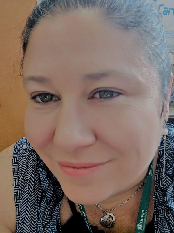 Mulher de pele clara, olhos verdes e cabelo escuro preso puxado para trás.