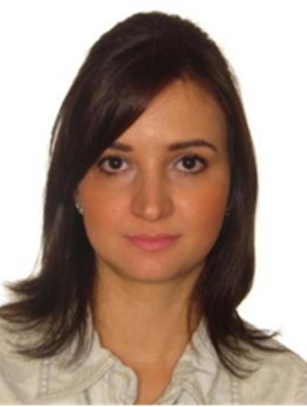 Mulher de pele morena clara, cabelos na altura dos ombros escuros, olhos escuros.