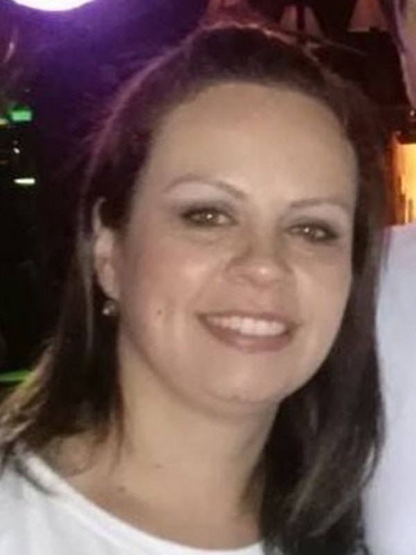 Mulher sorridente de pele clara e cabelos castanhos, lisos e compridos.