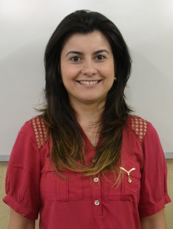 Mulher sorridente de pele clara, cabelos castanhos lisos e repicados, com as pontas descoloridas.