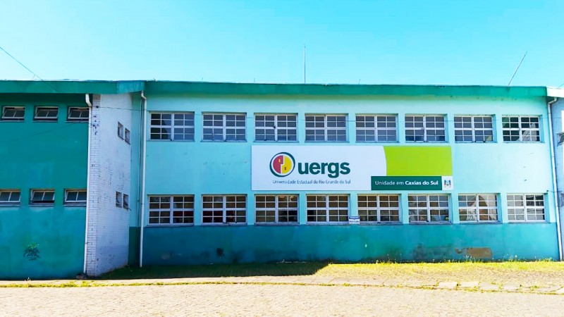 Pr&eacute;dio de 2 andares com paredes em tom de azul e muitas janelas. Ao centro, na parede, a placa de identifica&ccedil;&atilde;o da Uergs.