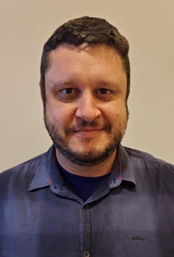 Homem de pele morena clara, olhos e cabelos curtos escuros.